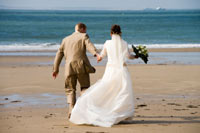 A Bride and groom walking on the beach